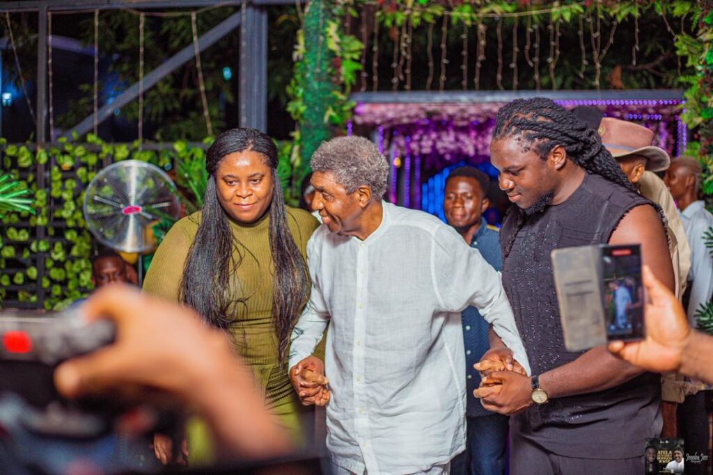 Francis Atela leading legendary Nigerian musician Bongos Ikwue by the hand on stage during their collaborative folk music concert tour.