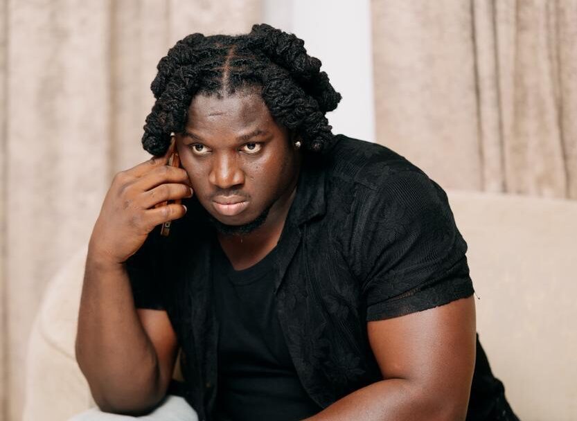 Pensive portrait of Nigerian folk singer Francis Atela sitting thoughtfully during a promotional studio photoshoot.